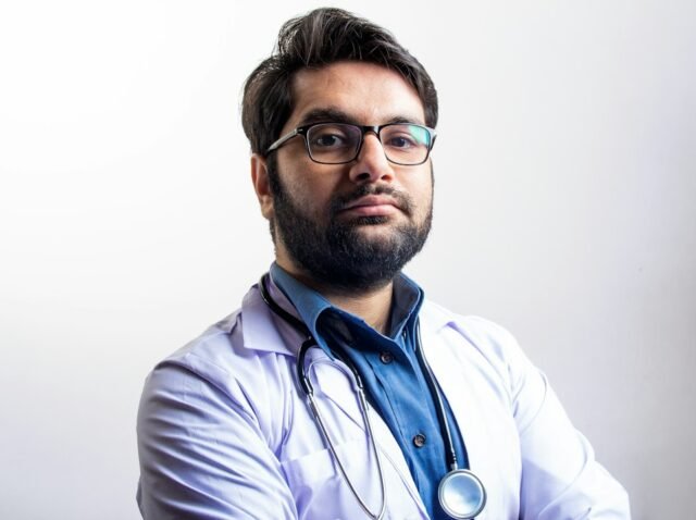 Physician reviewing a personal brand website and professional profile on a laptop in a modern clinic office