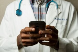 Klinikte akıllı telefonla hasta mesajlarını yanıtlayan sağlık çalışanı