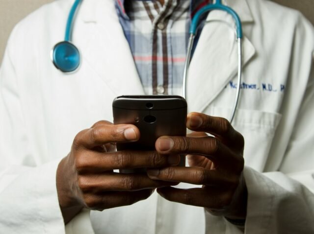 Klinikte akıllı telefonla hasta mesajlarını yanıtlayan sağlık çalışanı